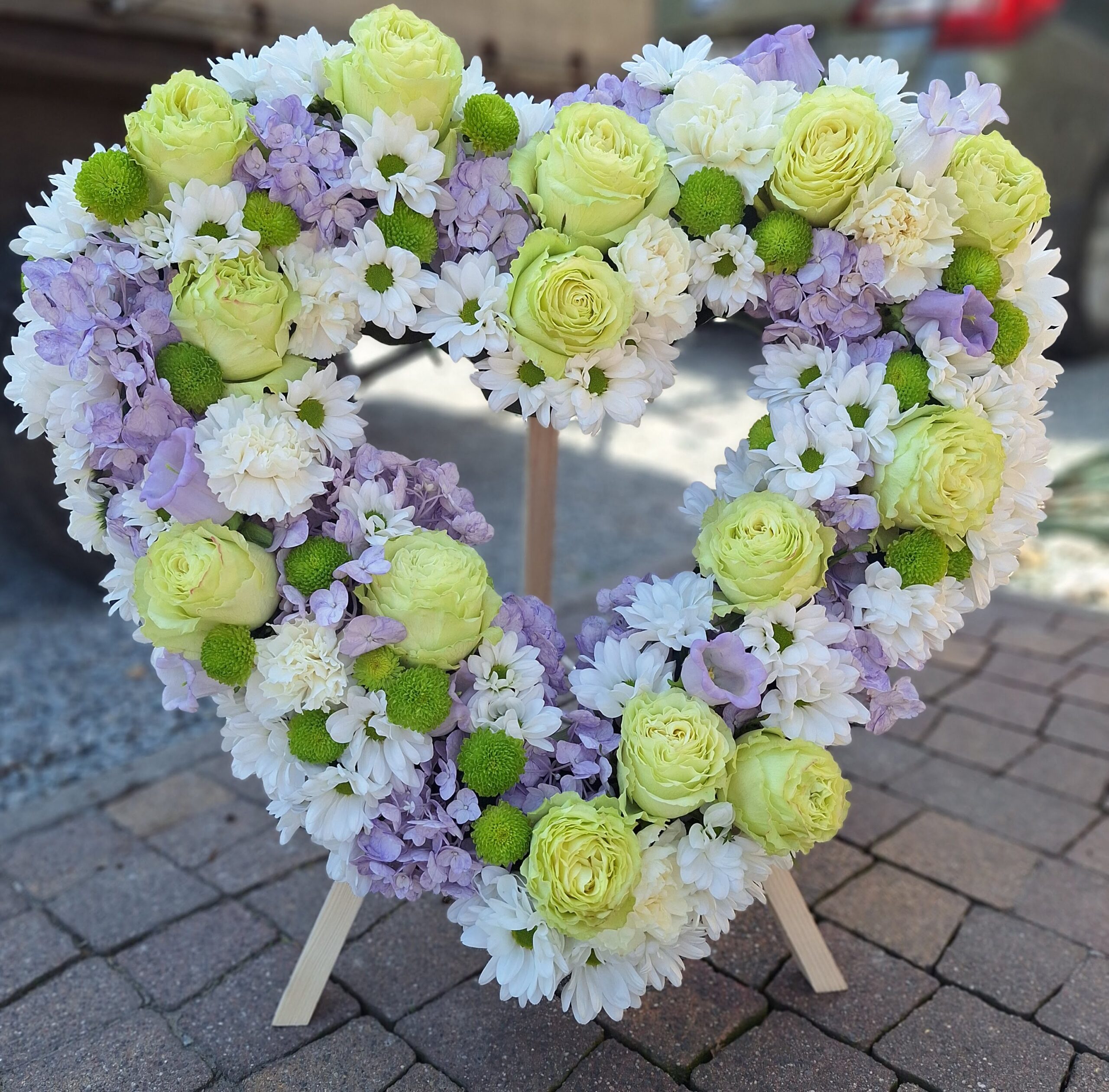 wieniec pogrzebowy w kształcie serca z zielonymi różami i fioletową hortensją