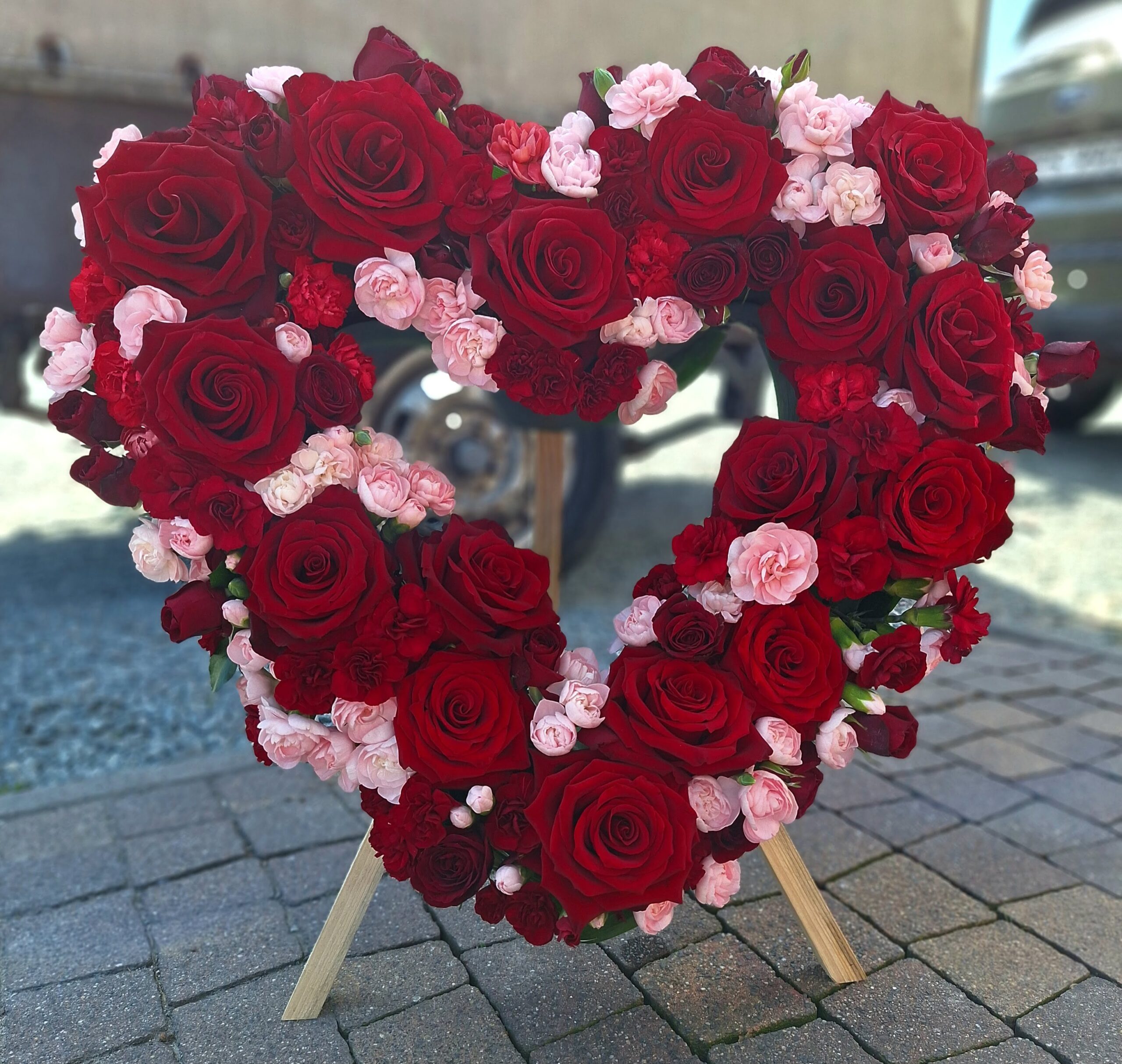 wieniec w kształcie serca z czerwonych róż i różowych goździków